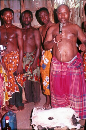 The chief and ritual specialist with others inside the ancestral village shrine in Abuma